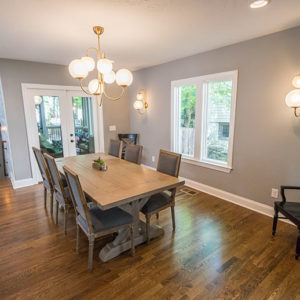 A well-lit dining room addition with a large window and door that leads to a sunroom.