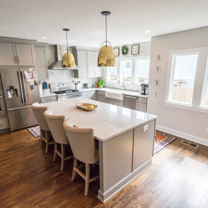 A well-lit kitchen focusing on a beautiful kitchen island with a white marble countertop.