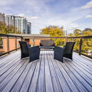 A skyline view from a dark wood balcony. The balcony is furnished with 3 dark accented patio chairs.