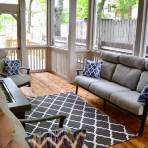 A well-lit screened-in porch with white trim and natural wood flooring.