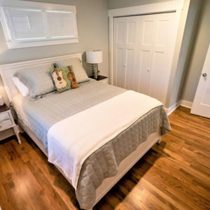 A bedroom addition with natural wood flooring and double door closet.