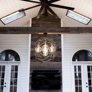 An inside view of an enclosed deck with a modern lighting fixture and skylights.