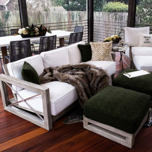 An upclosed shot of white patio furnitue in a covered deck with metal railings. The deck is a dark wood color.