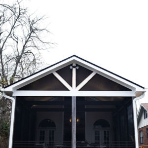 A white trimmed and covered balcony with a metal railing.