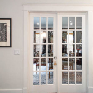 Two white french doors leading to a dining room