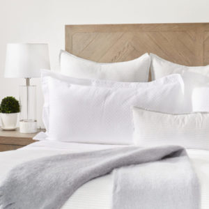 Queen bed with white comforter and a grey blanket