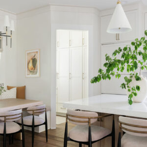 An open view of a new modern kitchen with a breakfast nook, marble island, and kitchen pantry with white cabinets.