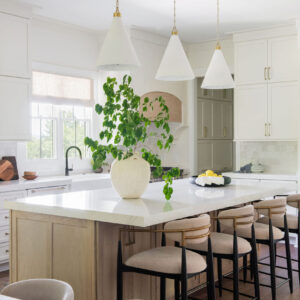 A well lit open space kitchen with white cabinets and a large white marble kitchen island.