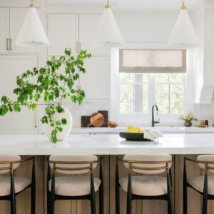 A new open space kitchen remodel with a white marble kitchen island, decorated with a green plant and bowl of lemons.