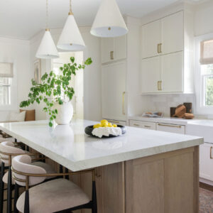 A side view of a kitchen remodel with a brand new marble top island and modern white cabinets.