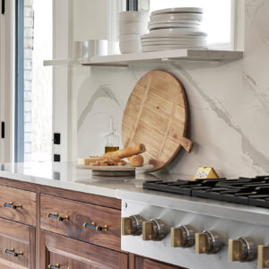 An upclose shot of a custom cabinet remodel and cooktop. The cabinets are made of a dark wood and have a white marble countertop.