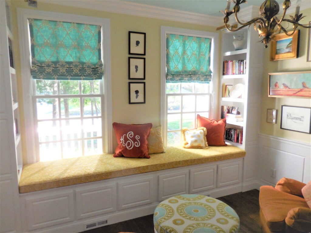 A bright and cozy window seat area with colorful cushions, built-in shelves, and ample natural light.