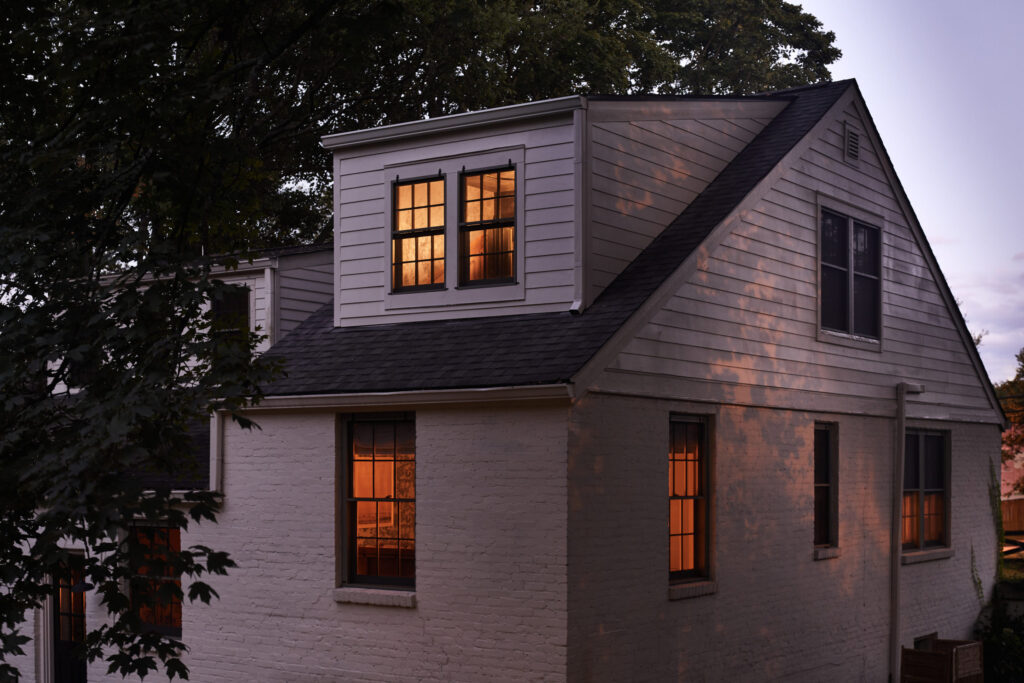 Exterior view of a home addition with lit windows at dusk.
