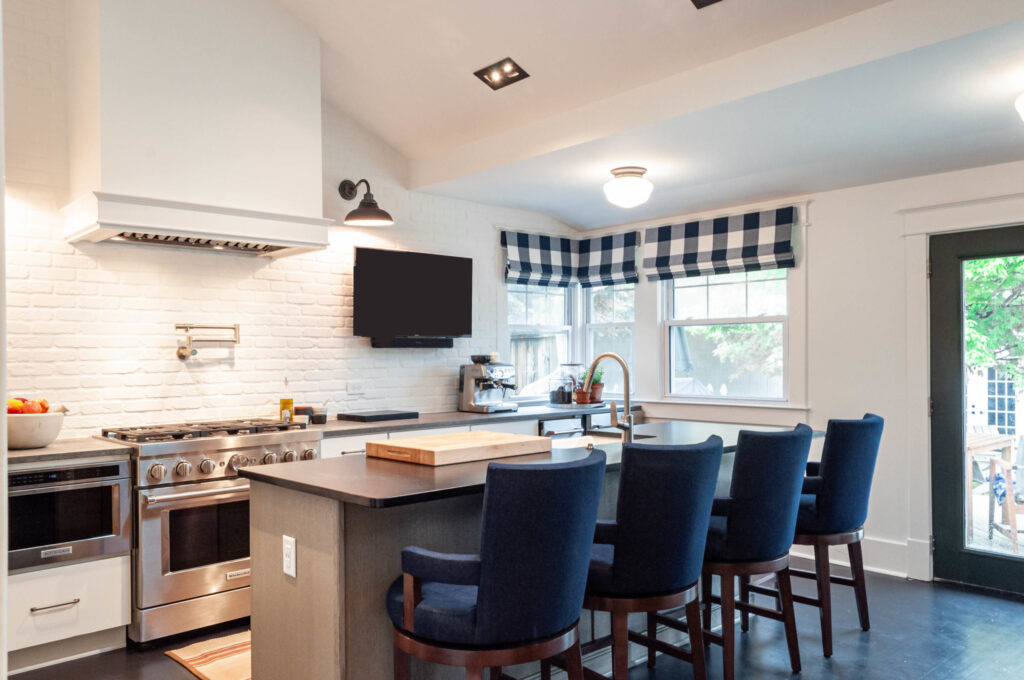 A modern kitchen with a central island, navy-blue seating, and white-brick accents.