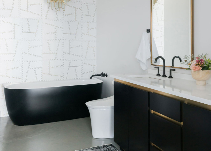 Modern bathroom with a black freestanding tub, marble vanity, and gold-accented fixtures.
