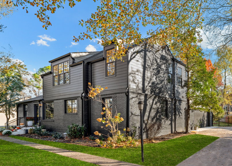 Modern custom-built home with a dark exterior and rich landscape.