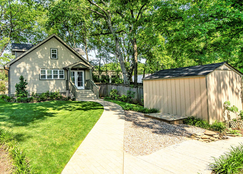 Cottage-style accessory dwelling unit with a garden and pathway leading to the entrance.