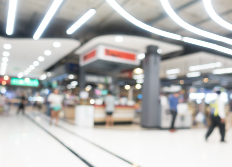 Brightly lit retail space with display fixtures and customers in the background.