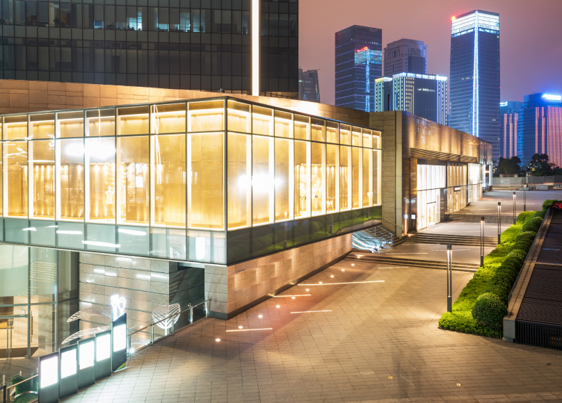 Commercial building with large illuminated glass windows in a modern architectural design.