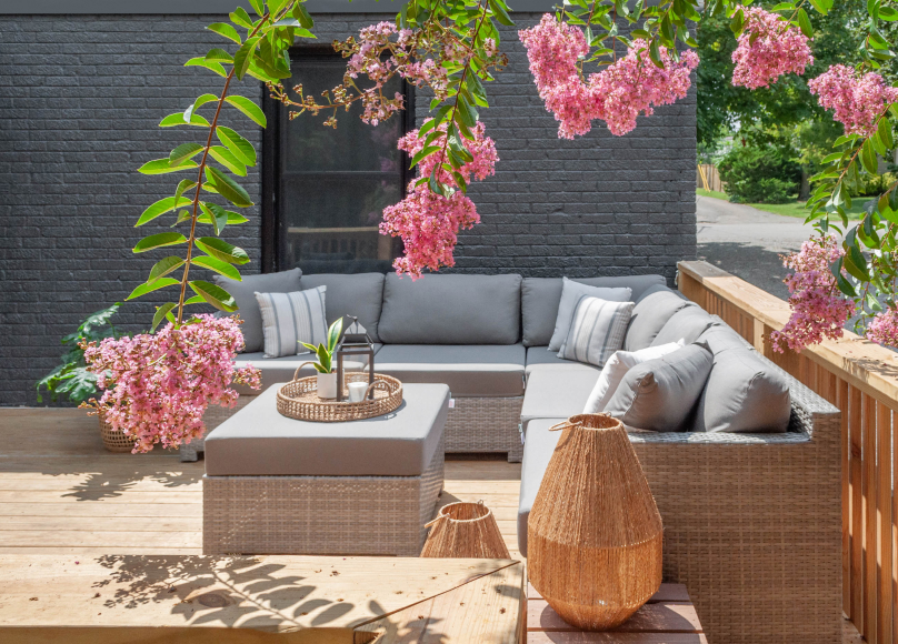 Stylish outdoor living area with a comfortable sectional surrounded by blooming pink flowers.