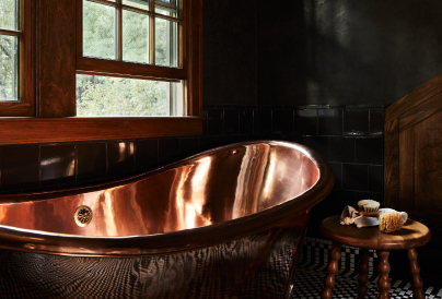 Luxurious bathroom with a polished copper bathtub under a window.