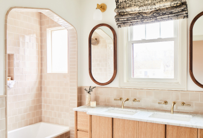 Elegant bathroom with a double vanity, arched shower entry, and warm beige tones.