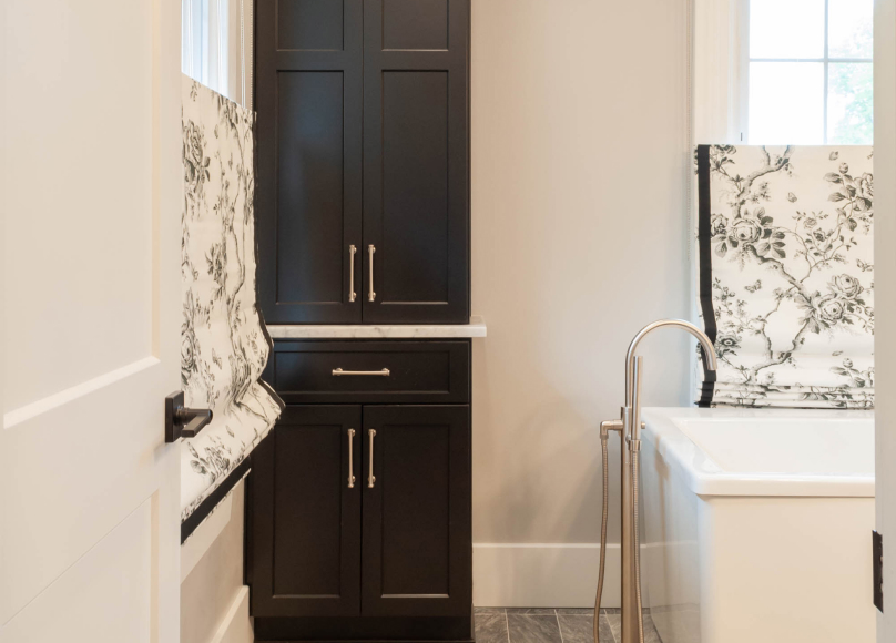 Bathroom featuring custom dark cabinetry and a freestanding tub.