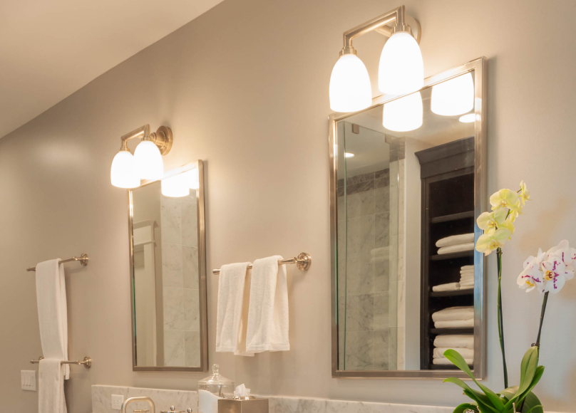 Bathroom lighting update with dual mirrors and elegant overhead fixtures.