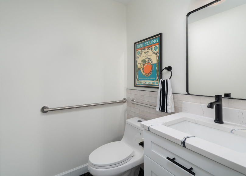 Powder room featuring a sleek white vanity and grab bar for accessibility.