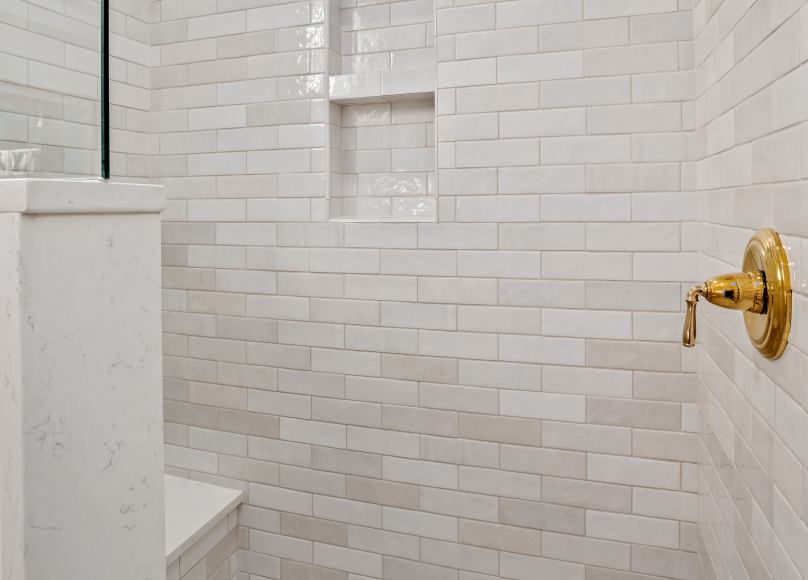 Walk-in shower with white subway tile and a built-in shelf.