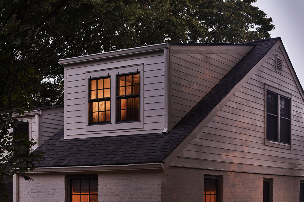 House exterior with lit upper windows at dusk.